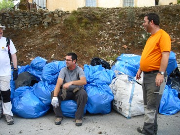 Imagen de uno de los participantes sentado sobra la cantidad de basura recogida