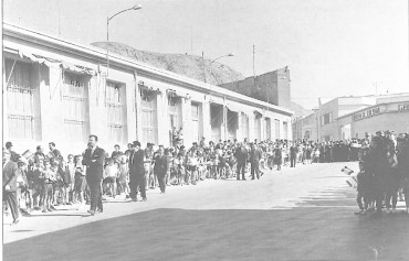 25 de octubre de 1964. Numerosos niños aguardan la llegada del obispo portando banderitas para saludarlo. Al fondo, el clero.